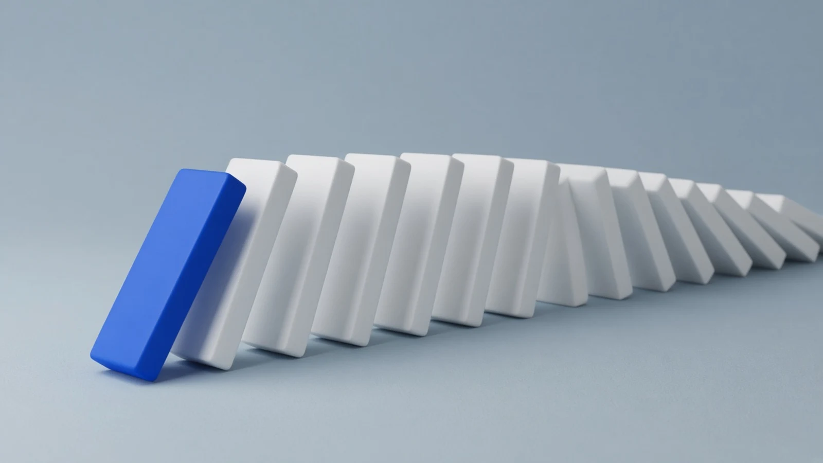 A row of white dominoes with the first blue domino tipping forward