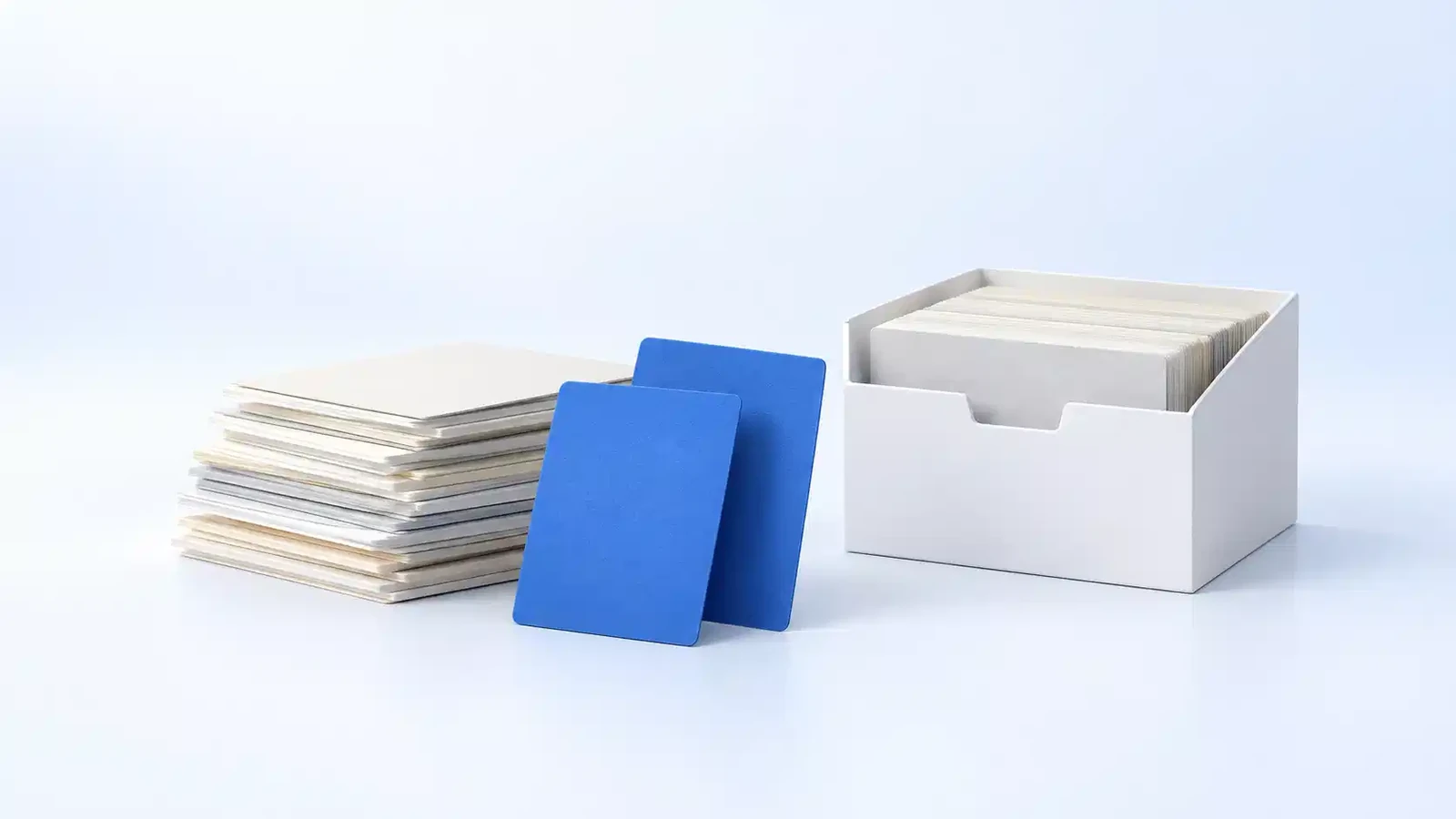 A low stack of faded old cards with two blue cards lifted out and standing in front, and the rest filed neatly in an open box beside them.
